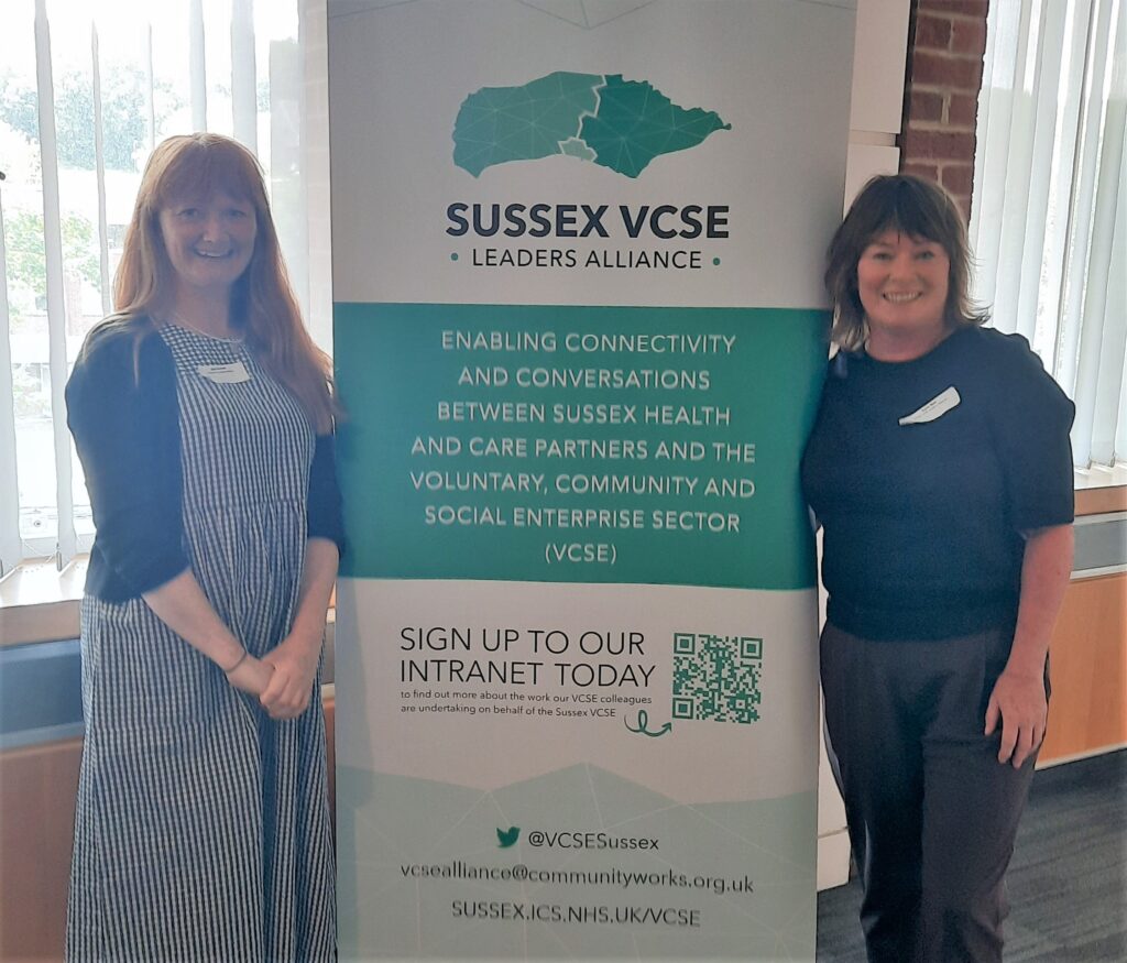 Two women standing next to banner