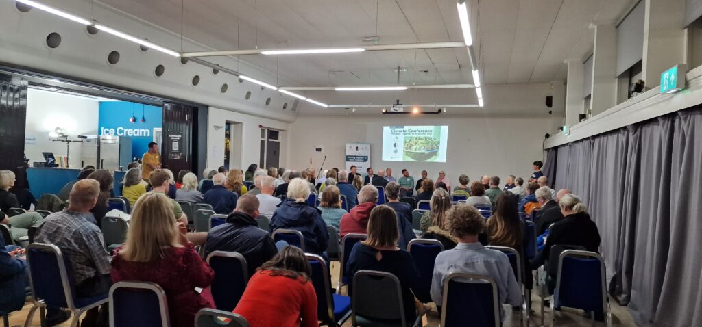 Large room of people watching a slide presentation