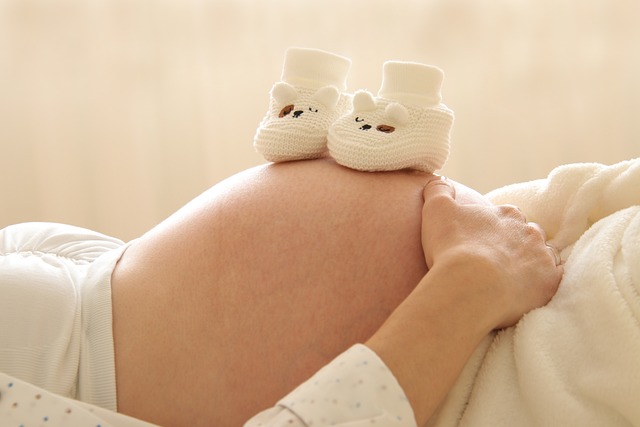 Close up of pregnant belly with cute baby booties on top
